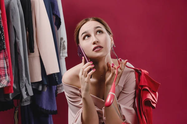 Beautiful girl choosing clothes speaks on the phone
