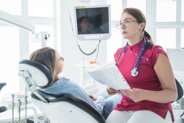 Diş hekimi, dişçi muayenehanesinde bir hastaya danışır.