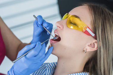 A dentist examines a patient, close-up of a patient with an open mouth next to which dental objects clipart