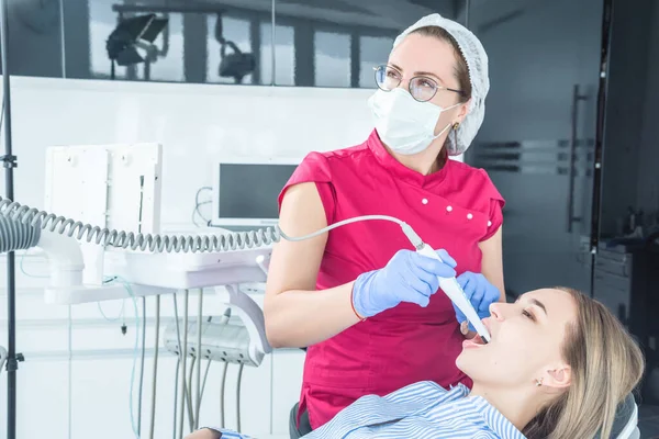 El médico dentista mira con un microscopio los dientes del paciente — Foto de Stock