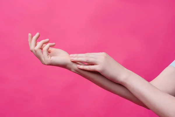 Lindas, jovens mãos femininas em um fundo rosa. Higiene, frescura e conceito de cuidados com a pele, mãos de um massagista ou cosmetologista, indústria de salões de beleza e spas — Fotografia de Stock
