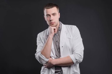 Gri arkaplanlı, sağlık ceketli genç ve güzel bir adam. Tıp eğitimi ve tıbbi aktivite kavramı