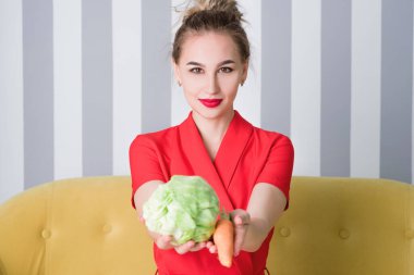 Güzel bir kız elinde lahana tutuyor, yiyormuş gibi yapıyor.
