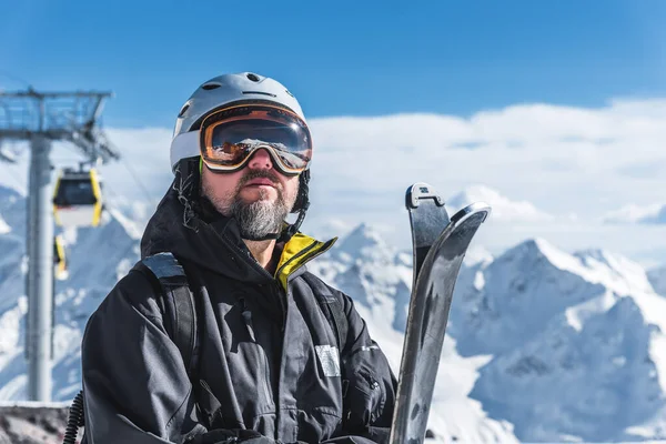 Um homem com esquis fica no alto das montanhas apreciando a paisagem. Desça esqui, relaxamento extremo — Fotografia de Stock