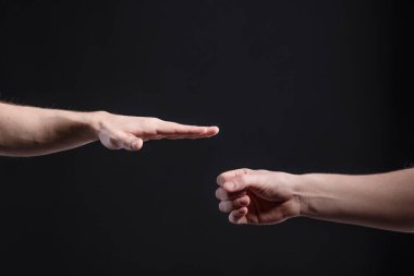 Erkekler karanlık arka planda, taş, makas, kağıt oynuyorlar. Yüzleşme ve rekabet kavramı, oyunlar
