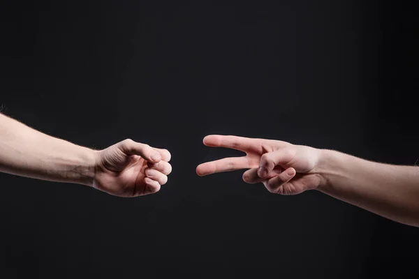 Manos de hombre sobre un fondo oscuro, mostrar un juego de piedra, tijeras, papel. El concepto de confrontación y rivalidad, juegos — Foto de Stock