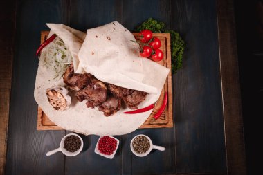 İştah açıcı kızarmış et, ahşap bir tepside, baharatların arasında yatıyor. Yemek endüstrisindeki yemek fotoğrafçılığı, karanlık arka plan.