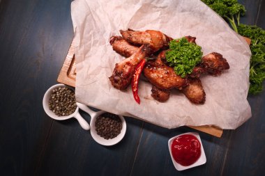 Ahşap tepside kızarmış tavuk kanadı. Yemek endüstrisindeki yemek fotoğrafçılığı, karanlık arka plan.