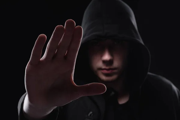 A man in a black hood on a black background, studio photography. The idea of mysticism, mystery, crime and deception — Stock Photo, Image