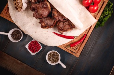 İştah açıcı kızarmış et, ahşap bir tepside, baharatların arasında yatıyor. Yemek endüstrisindeki yemek fotoğrafçılığı, karanlık arka plan.