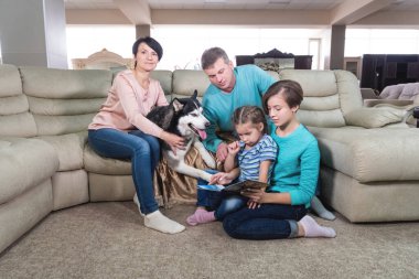 Anne, baba ve iki kız hafta sonları evde rahatlar ve köpekle oynarlar. Evde birlikte vakit geçiren ideal aile kavramı.