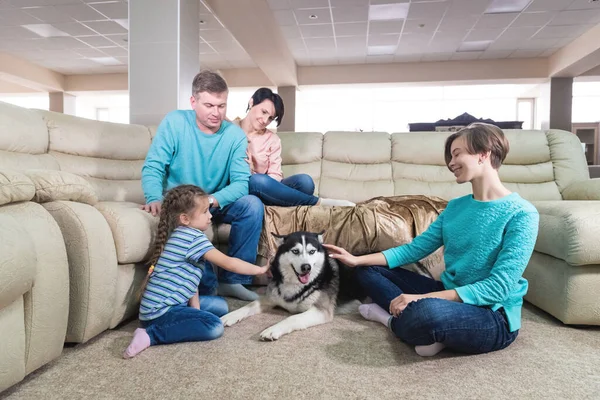 Mamá, papá y dos hijas se relajan en casa y juegan con el perro los fines de semana. El concepto de una familia ideal que pasa tiempo en casa juntos — Foto de Stock