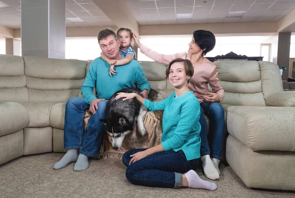 Mamá, papá y dos hijas se relajan en casa y juegan con el perro los fines de semana. El concepto de una familia ideal que pasa tiempo en casa juntos — Foto de Stock