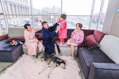 Anne, baba ve iki kız hafta sonları evde rahatlar ve köpekle oynarlar. Evde birlikte vakit geçiren ideal aile kavramı.