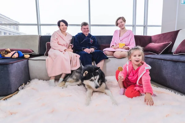 Mom, dad and two daughters relax at home and play with the dog on weekends. The concept of a ideal family who spends time at home together