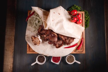 İştah açıcı kızarmış et, ahşap bir tepside, baharatların arasında yatıyor. Yemek endüstrisindeki yemek fotoğrafçılığı, karanlık arka plan.