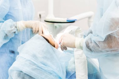 Diş implantı ameliyatı sırasında bir ameliyathanede dişçi ve hemşire cerrahın ellerini yakın plan çektir.