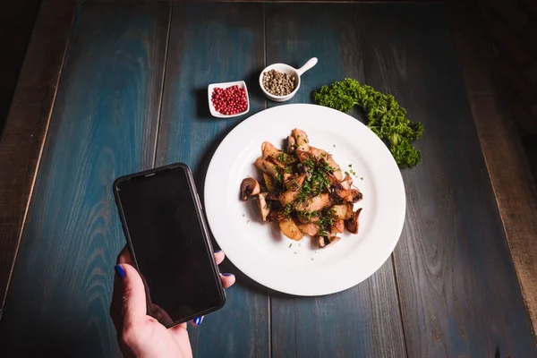 Zbliżenie rąk z telefonem na tle talerza z kolacją w kawiarni. Koncepcja szybkiego zamawiania i dostawy żywności — Zdjęcie stockowe