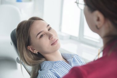 Diş hekimi, diş muayenehanesinde sandalyeye oturan bir hastaya danışıyor. Sağlık, diş sağlığı ve sağlık hizmetleri kavramı