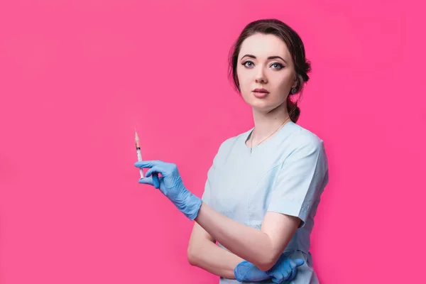 Женщина-косметолог-врач со шприцем в руках на розовом фоне в студии. Концепция косметологии, медицины и красоты — стоковое фото