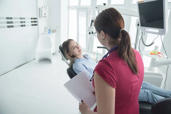 Стоматолог консультирует пациента, сидящего в кресле в стоматологическом кабинете. Концепция здравоохранения, стоматологических услуг и здравоохранения — стоковое фото