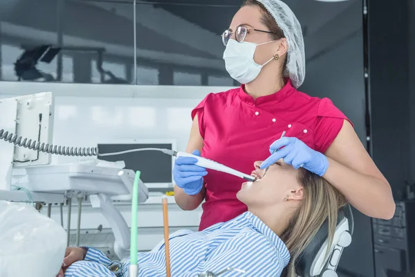 El dentista examina a un paciente en una recepción en el consultorio dental. El concepto de atención y tratamiento de la salud en las instalaciones médicas — Foto de Stock