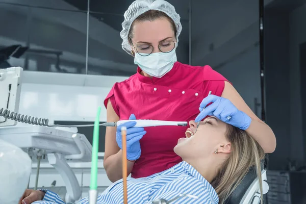 El dentista examina a un paciente en una recepción en el consultorio dental. El concepto de atención y tratamiento de la salud en las instalaciones médicas — Foto de Stock