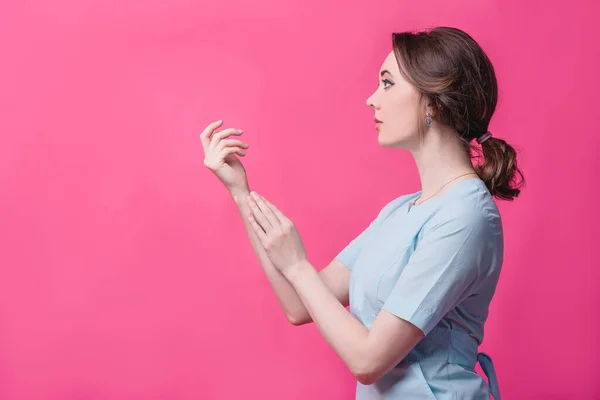 Menina bonita toca suavemente as mãos em um fundo rosa no estúdio. O conceito de beleza, cuidado, cosmetologia e massagem — Fotografia de Stock