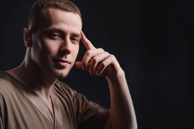 Karanlık bir arka planda dalgın dalgın duran çekici genç adam. Stüdyo fotoğrafçılık