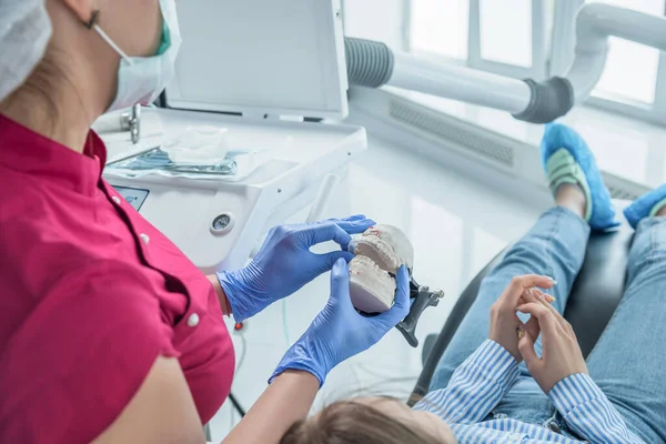 Kadın dişçi doktor diş koruyucusunu elinde tutuyor, dişlerini düzeltmek için alçıya alıyor. Tıp merkezlerinde sağlık ve tedavi kavramı