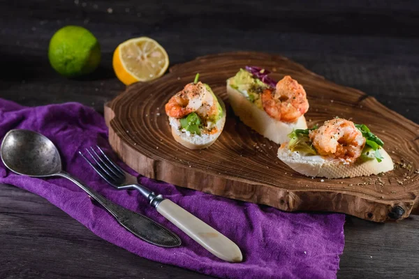 Sandwiches with shrimp, cheese and avocado on a wooden tray on the table, dark background. The concept of nutrition and beautiful serving of food — Stock Photo, Image