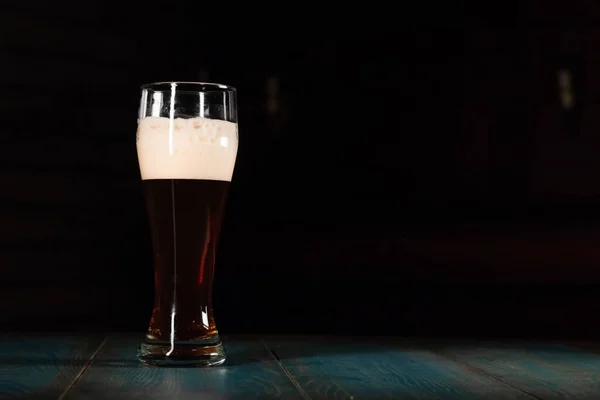 Bier auf dunklem Grund auf einen Holztisch geschüttet. Das Konzept der Entspannung und des Zeitvertreibs — Stockfoto