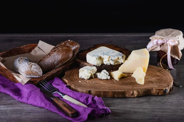 Ost och bröd på ett trästativ på bordet mörk bakgrund. Begreppet kost och vacker servering av mat. — Stockfoto