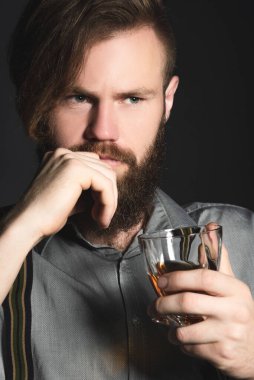 Elinde bir bardak alkolle izole edilmiş siyah bir arka planda dalgın genç bir adamın portresi. Eğlence, dinlenme ve rahatlama kavramı.