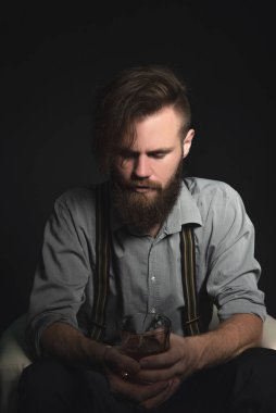 Elinde bir bardak alkolle izole edilmiş siyah bir arka planda dalgın genç bir adamın portresi. Eğlence, dinlenme ve rahatlama kavramı.