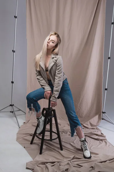 Retrato de uma linda garota que posa deitada no chão no estúdio, em um fundo bege — Fotografia de Stock