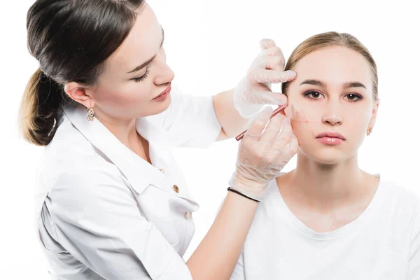 Косметолог осматривает лицо пациентки и планирует провести серию косметических процедур — стоковое фото