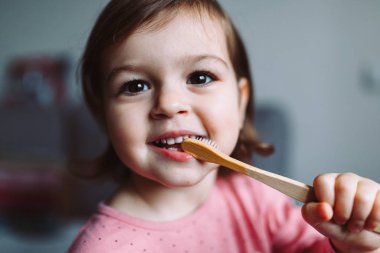 Küçük kız çevre dostu diş fırçasıyla oynuyor.