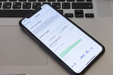 MOSCOW / RUSSIA - 4 Nisan 2020: iPhone 11 Pro bir MacBook klavyesinde yer almaktadır. Pil koruyucu kipini ayarlamak için menü ekranında