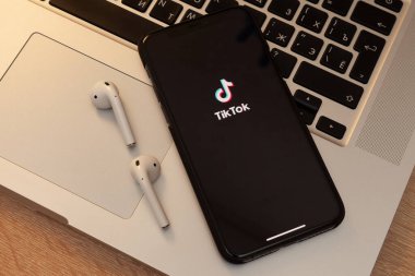 Moskova / Rusya - 18 Mayıs 2020: Siyah iPhone 11 Pro ve Airpod 'lar MacBook klavyesinde. Ekranda, TikTok uygulaması.
