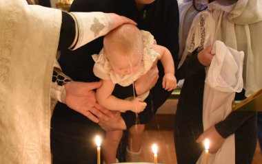 Kilisede bir çocuğun vaftiz töreni. Rahip çocuğu kutsal suyla yıkar.