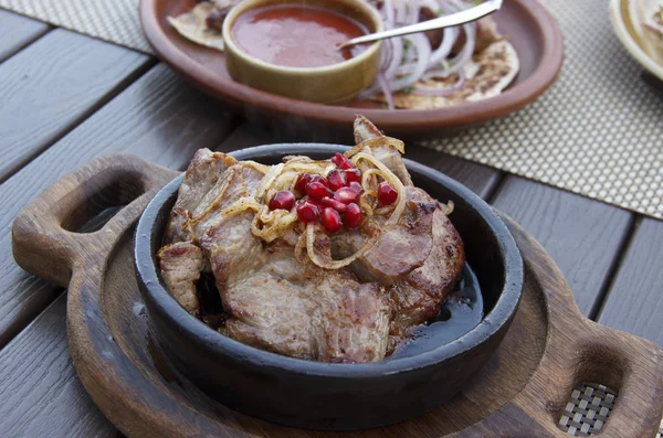 Heerlijke Georgische keuken. gebakken vlees in een kleipan, geserveerd met uien en granaatappelpitten — Stockfoto
