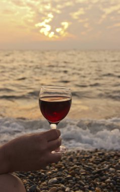 Elinde bir kadeh kırmızı şarap vardı. Gün batımında deniz kenarında romantik bir gün. Düğün ya da Sevgililer Günü kutlamaları.