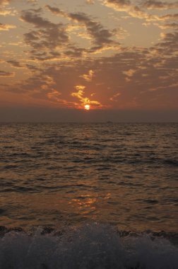 Su üzerindeki dramatik bulutlu manzara. Deniz kıyısında güzel bir gün batımı.