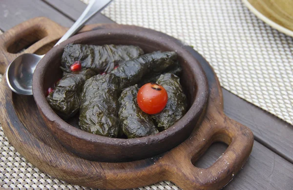 Tradisjonell georgisk dolma i drueblader på rustiskt trebord – stockfoto