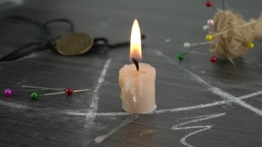 Büyülü bir çemberde yanan bir mum, okült iğnelerin yanında. Bir seans düzenlemek, mistik bir ritüel..