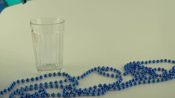 玻璃杯中的蓝色液体，白色底座上有冰块 — 图库视频影像