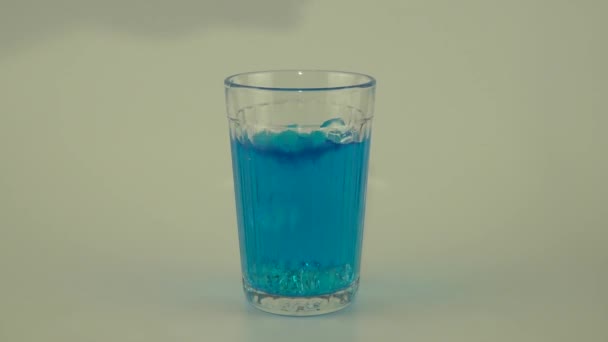 liquide bleu dans un verre avec glace sur fond blanc 
