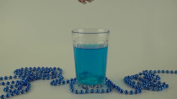 Blauwe vloeistof in een glas met ijs op een witte achtergrond — Stockvideo