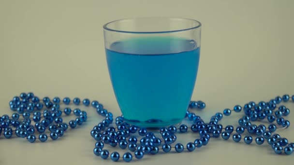 Liquide bleu dans un verre avec glace sur fond blanc — Video